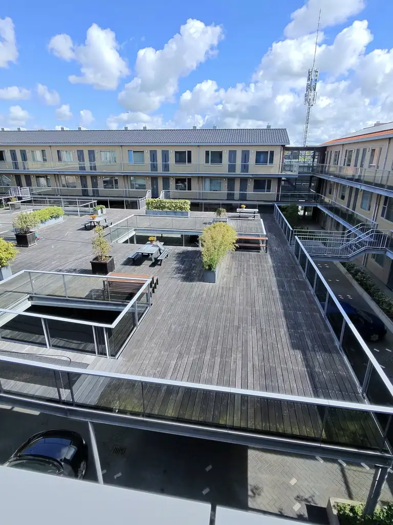 Vergrijsde houten vlonders op een binnenterras in Heiloo — voor de reiniging
