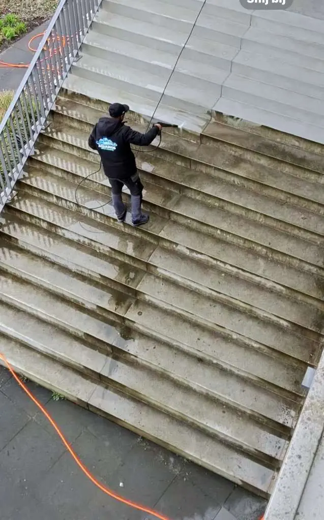 Vakman reinigt een houten trap met een hogedrukspuit