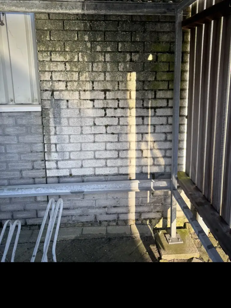 Metselwerk aan de schaduwzijde, zwartgroen van de alg, op de Beverkoog in Alkmaar — voor de reiniging