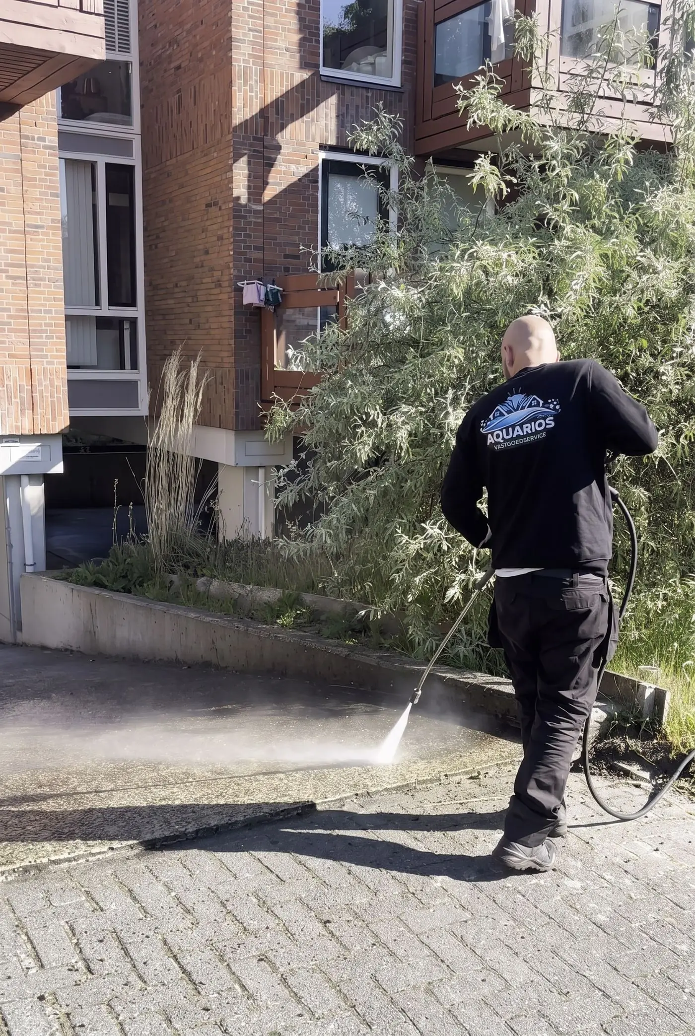 Aquarios reinigt met hogedruk de bestrating bij een woning